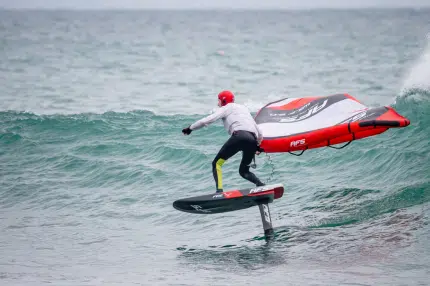 Un homme fait de la planche à voile sur une vague